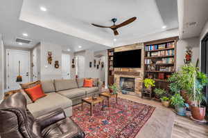 Living room featuring ceiling fan, arched walkways, wood finished floors, recessed lighting, and a fireplace