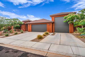 Mediterranean / spanish home with a tiled roof, an attached garage, stucco siding, and concrete driveway