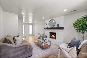 Living area with wood finished floors, a fireplace, and recessed lighting