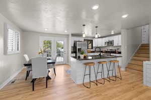 Kitchen featuring stainless steel appliances, dark countertops, white cabinetry, a kitchen breakfast bar, and recessed lighting