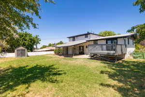 Back of house with a deck, a fenced backyard, a shed, brick siding, and a patio area