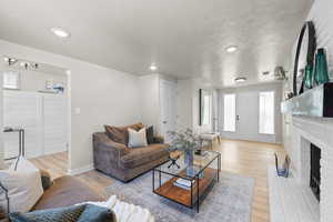 Living room with a fireplace, light wood-type flooring, a chandelier, and recessed lighting