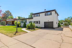 Tri-level home with brick siding, concrete driveway, a garage, and a chimney