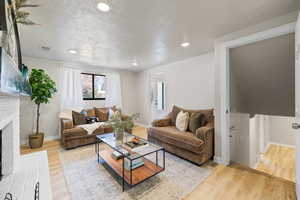 Living room featuring a brick fireplace, light wood-style flooring, and recessed lighting