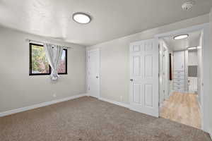 Unfurnished bedroom with light colored carpet and baseboards