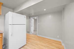 Kitchen with freestanding refrigerator and light wood-style flooring