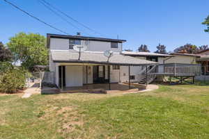 Rear view of house with a gate, brick siding, a deck, a patio, and a shingled roof