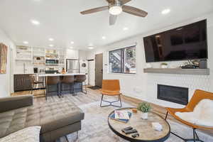 Living room with stacked washer / drying machine, light wood-type flooring, ceiling fan, recessed lighting, and a tiled fireplace