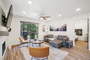 Living area featuring light wood-style flooring, a fireplace, ceiling fan, and recessed lighting