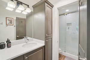 Bathroom featuring a stall shower, vanity, and wood finished floors