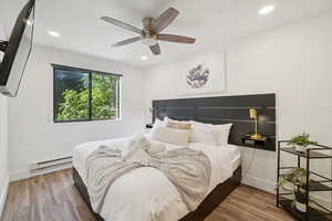 Bedroom featuring a baseboard radiator, wood finished floors, recessed lighting, and ceiling fan