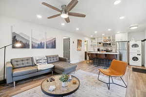 Living room featuring stacked washing machine and dryer, light wood finished floors, ceiling fan, and recessed lighting