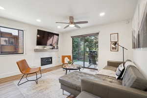 Living area featuring wood finished floors, ceiling fan, a glass covered fireplace, and recessed lighting