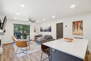 Living room with light wood finished floors, recessed lighting, a ceiling fan, and a fireplace