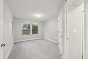 Spare room featuring light carpet and baseboards