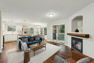 Living room with a glass covered fireplace, a textured ceiling, dark wood-style floors, and hanging lights