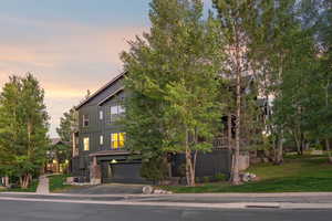View of front of property featuring an attached garage, asphalt driveway, a lawn, and board and batten siding