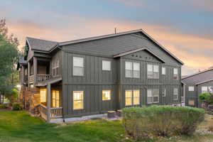 Back of house with board and batten siding, a yard, and roof with shingles