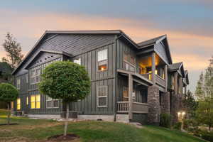 Property exterior at dusk with board and batten siding, a balcony, and a lawn