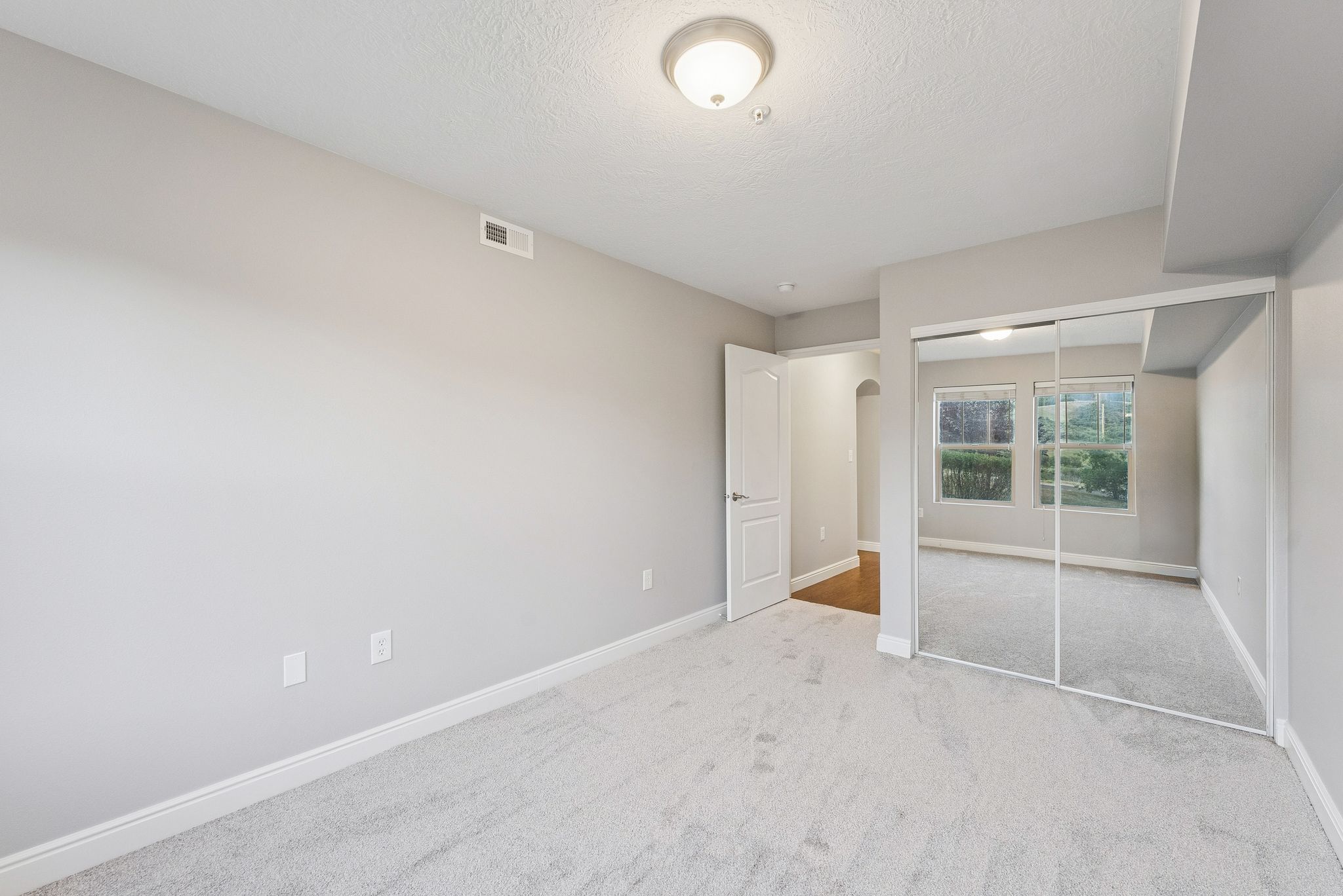 Unfurnished bedroom featuring a textured ceiling, a closet, carpet, and arched walkways
