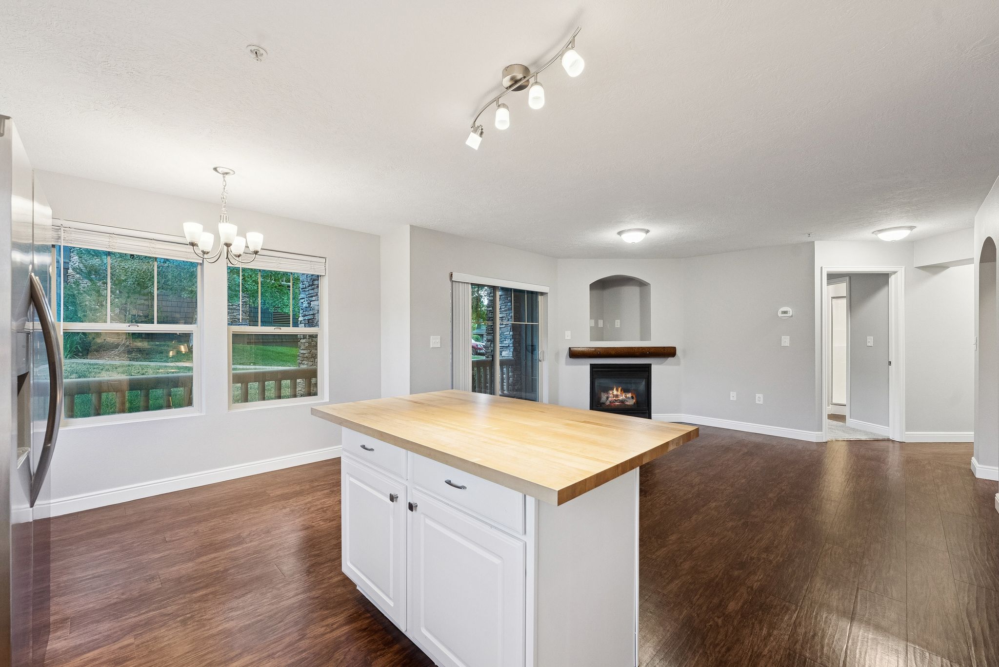 Kitchen featuring wood counters, stainless steel fridge with ice dispenser, dark wood-style floors, and a lit fireplace