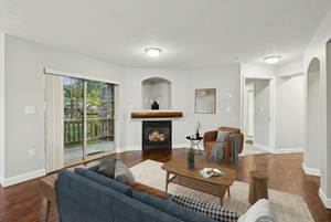 Living room with a glass covered fireplace, dark wood-type flooring, a textured ceiling, and arched walkways