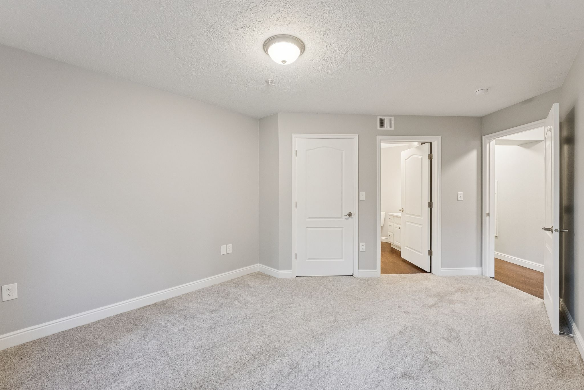 Unfurnished bedroom featuring carpet, a textured ceiling, and ensuite bath