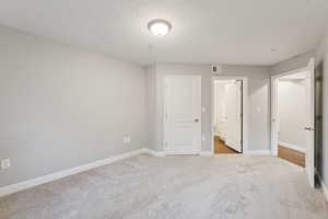 Unfurnished bedroom featuring carpet, a textured ceiling, and ensuite bath