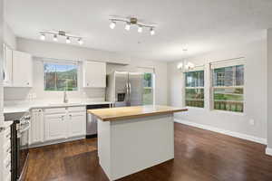 Kitchen featuring appliances with stainless steel finishes, wooden counters, white cabinets, and dark wood-style flooring