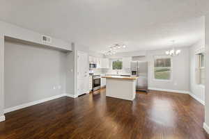 Kitchen featuring appliances with stainless steel finishes, dark wood-type flooring, a chandelier, light countertops, and a textured ceiling
