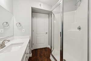 Full bath with a shower stall, vanity, and wood finished floors