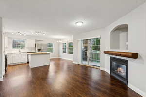 Unfurnished living room featuring a glass covered fireplace, a chandelier, dark wood-style flooring, and a textured ceiling