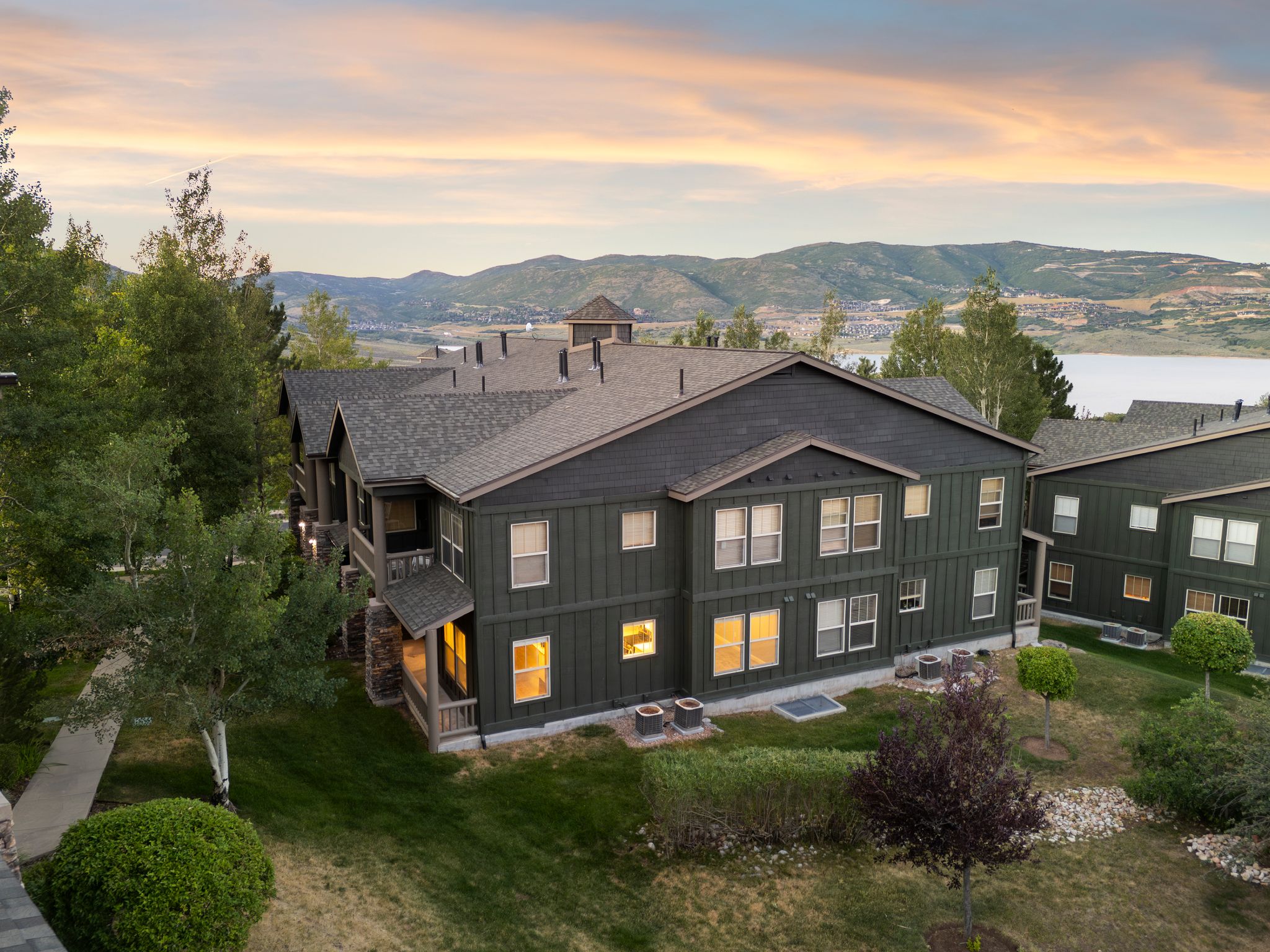 Back of property at dusk with roof with shingles, board and batten siding, a mountain view, and a lawn