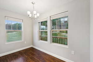 Unfurnished room featuring a chandelier and dark wood-style floors