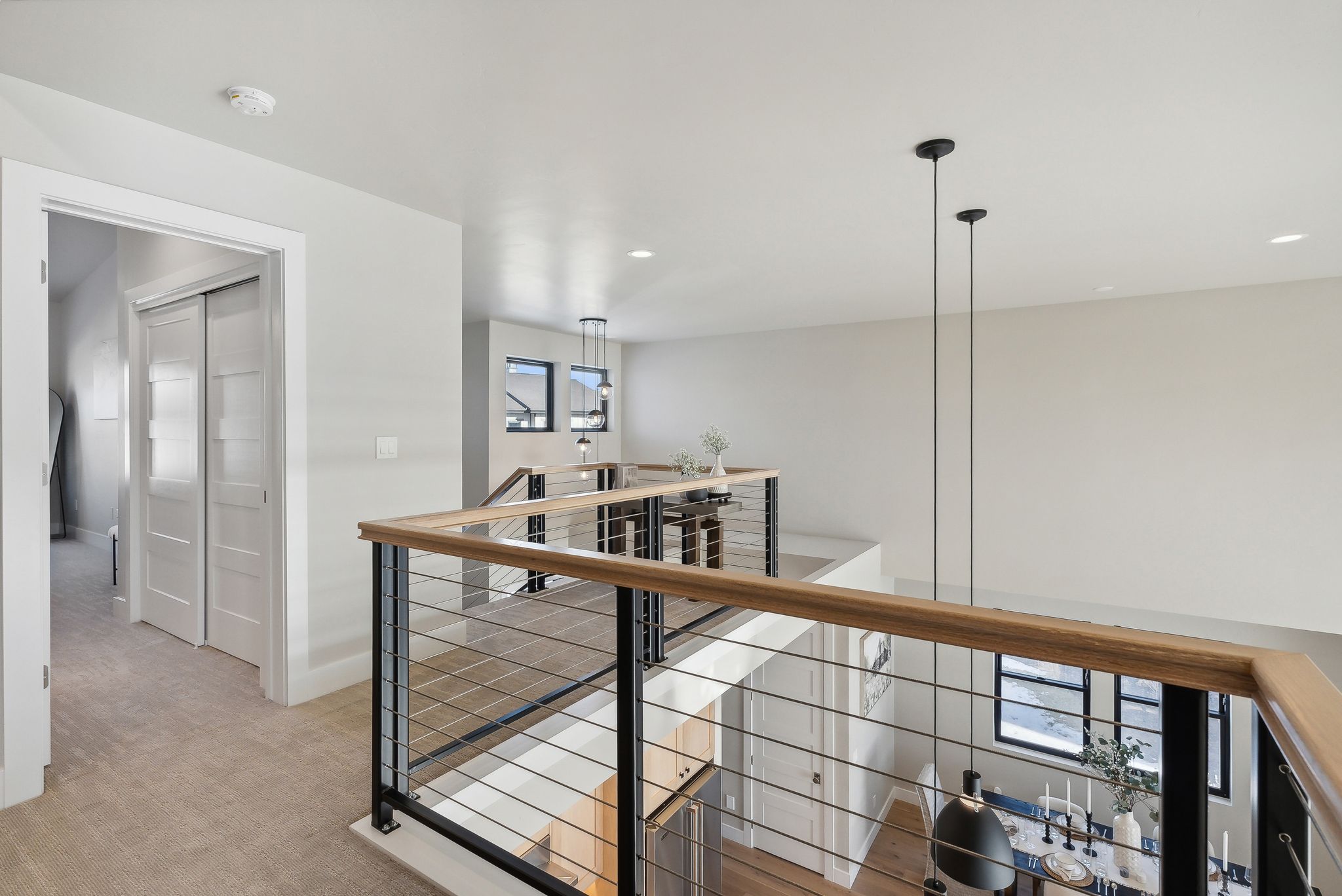 Hall with an upstairs landing, light colored carpet, and recessed lighting