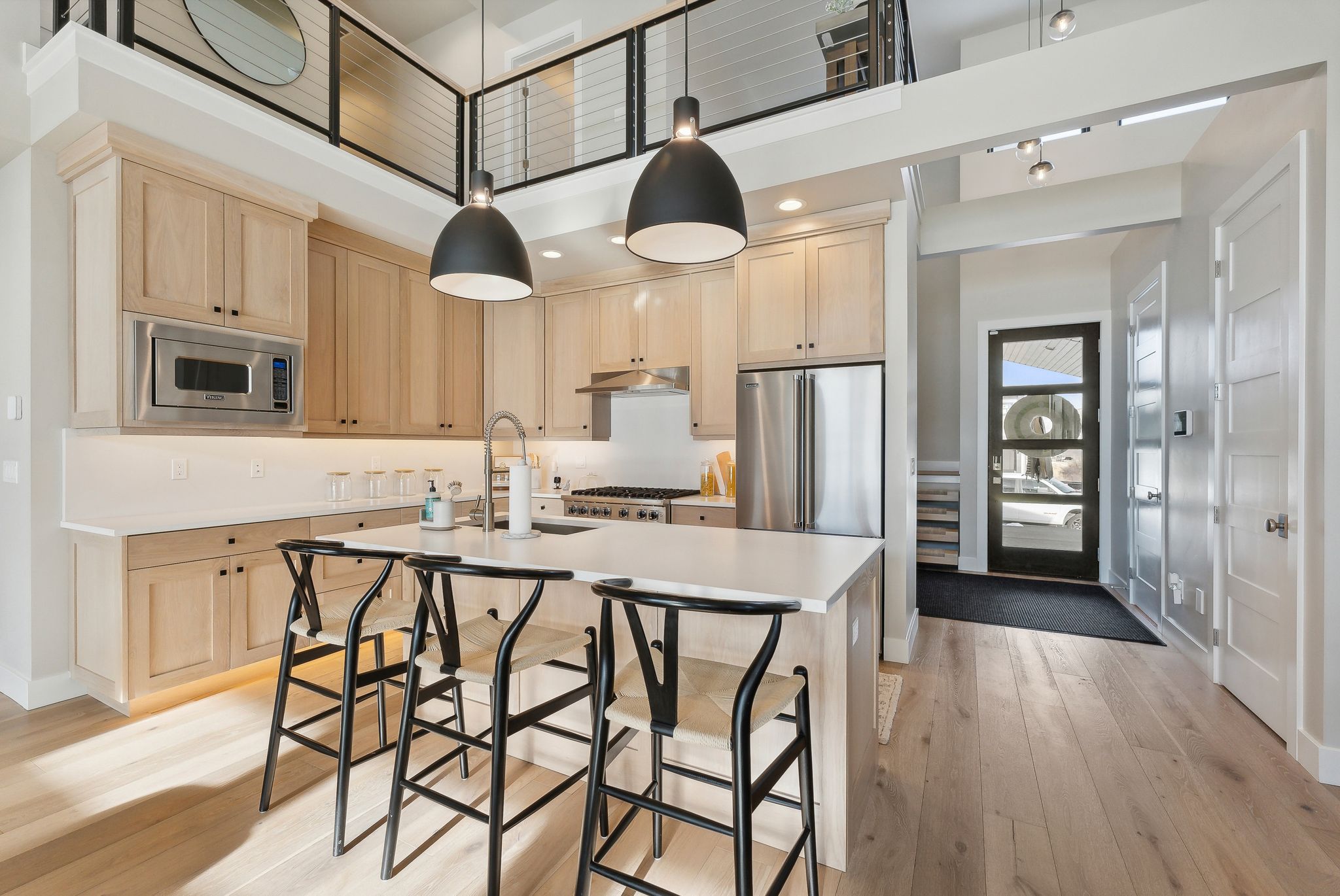 Kitchen with appliances with stainless steel finishes, light brown cabinetry, a high ceiling, light countertops, and light wood-type flooring