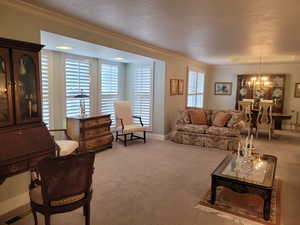 Living room featuring a chandelier, carpet, and crown molding