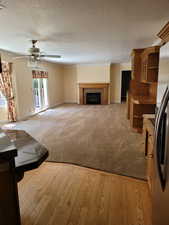 Unfurnished living room featuring ornamental molding, ceiling fan, light colored carpet, and a tile fireplace