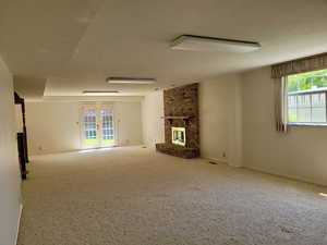 Unfurnished living room featuring a brick fireplace and carpet