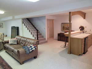 Living room featuring light colored carpet and stairs