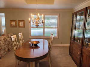 Dining room with carpet flooring, a chandelier, and crown molding