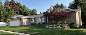 Ranch-style house featuring brick siding, a front lawn, and a garage