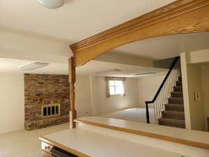 Below grade area featuring carpet, stairs, and a brick fireplace