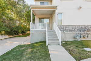 Property entrance featuring stucco siding, decorative rock, a porch, and a yard
