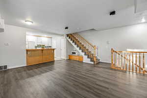 Open living room/kitchen area with stairways going up to the second floor and down to the garage.
