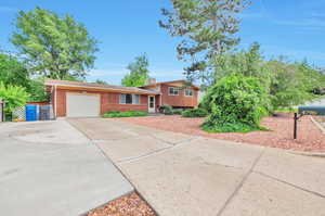Tri-level home featuring an attached garage, driveway, and brick siding