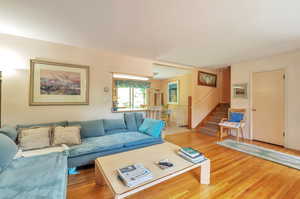 Living room with stairway and light wood-style floors