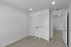 Bedroom featuring light colored carpet, recessed lighting, and a closet