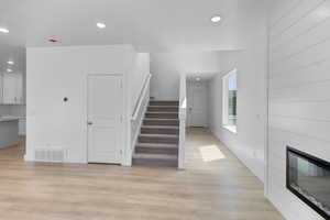 Entryway with wood finished floors and a large fireplace