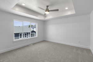 Primary bedroom featuring a tray ceiling, recessed lighting, and ceiling fan